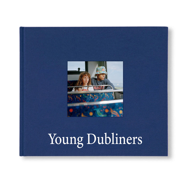 A navy hardcover book titled 'Young Dubliners' with a photograph of two individuals on the bus on the cover.