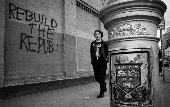 Person standing next to a graffiti-covered wall with 'Rebuild the Republic' written on it.