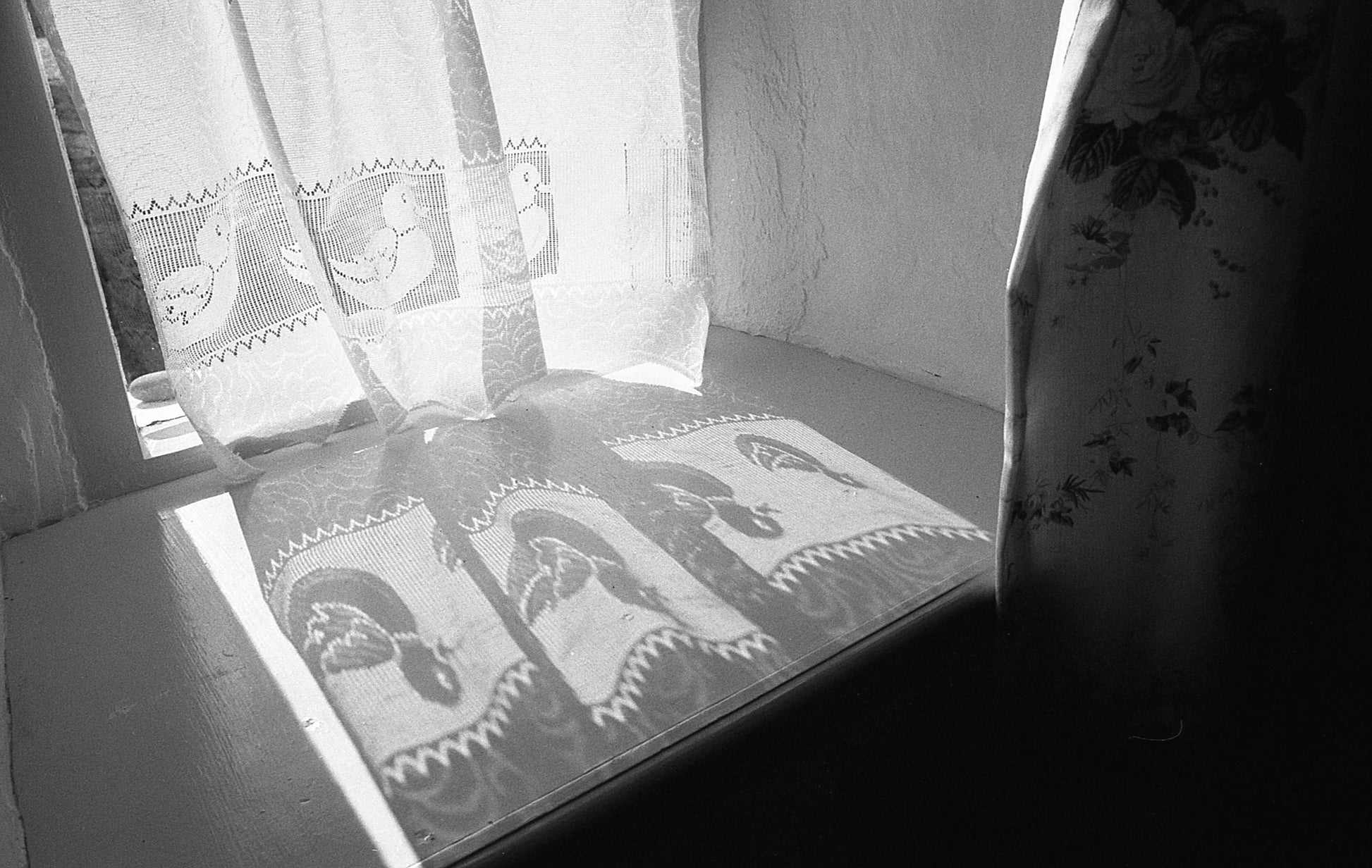 Decorative curtains with embroidered patterns casting shadows on a surface.