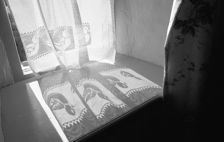 Decorative curtains with embroidered patterns casting shadows on a surface.
