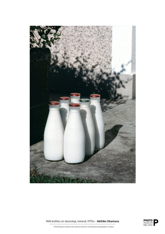 A photograph of several milk bottles placed on a doorstep, with a focus on the bottles against a blurred background.