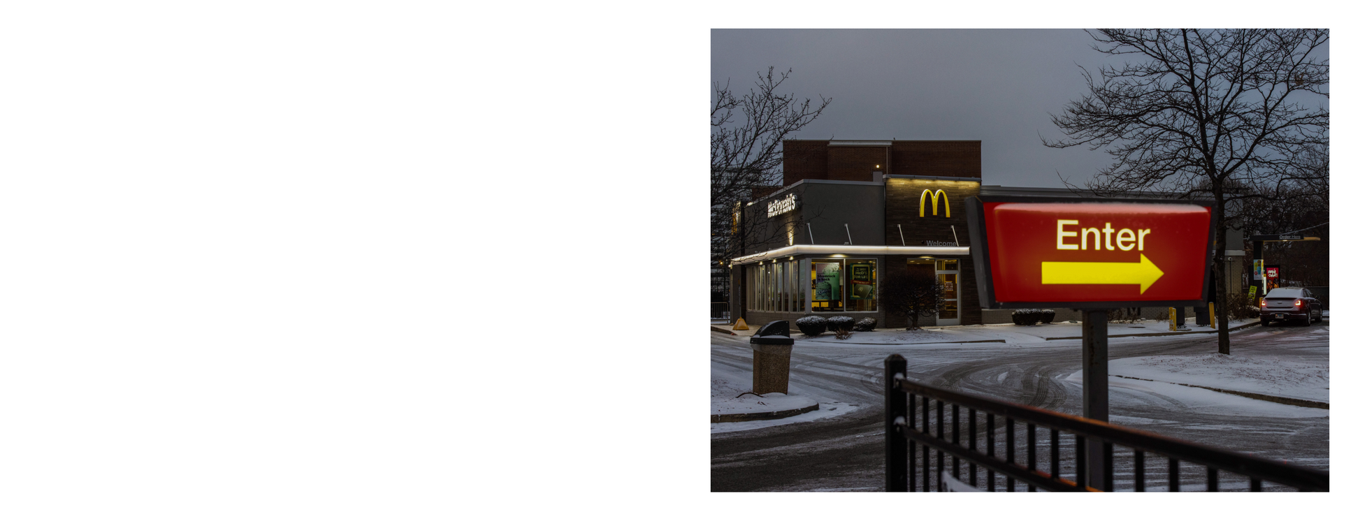 McDonald's restaurant entrance sign with 'Enter' and arrow in front of a building at night.