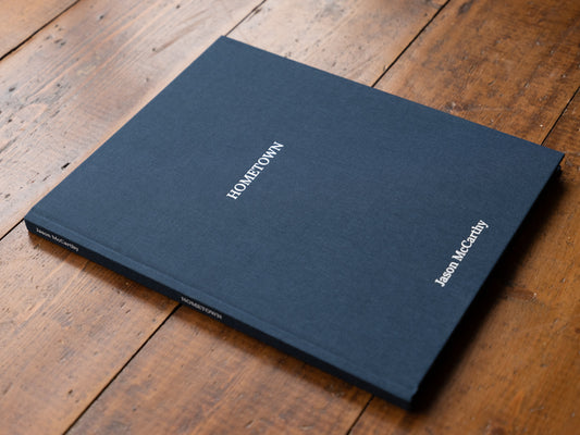 Blue book titled 'Hometown' by Jason McCarthy on a wooden surface